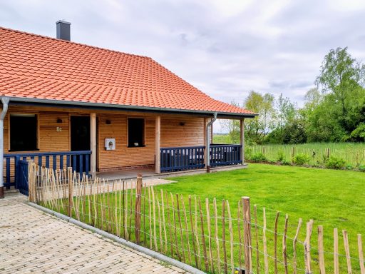 Einfamilienhaus mit rotem Dach, Holzverkleidung und grünem Garten.