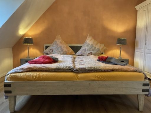 Helles Schlafzimmer mit einem Doppelbett, Nachttischen und warmen Wandfarben.