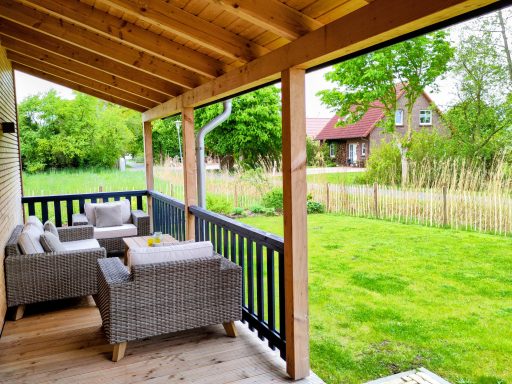 Gemütliche Terrasse mit Sitzgelegenheiten und Blick auf einen grünen Garten.