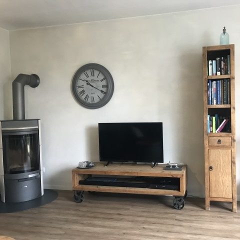 Moderner Wohnraum mit Fernseher, Holzregal, Uhr und Kamin.
