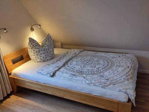 Holzbett mit dekorativem Kissen und einer gemusterten Decke im Schlafzimmer.