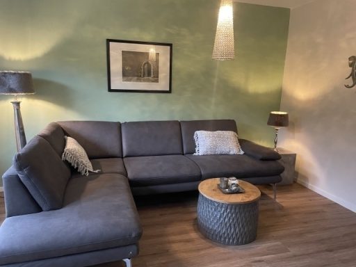 Gemütliches Wohnzimmer mit grauem Sofa, Beistelltisch und dekorativer Beleuchtung.