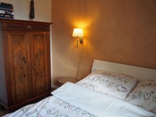 Ein Schlafzimmer mit einem Bett, einem Kleiderschrank und einer Wandlampe.